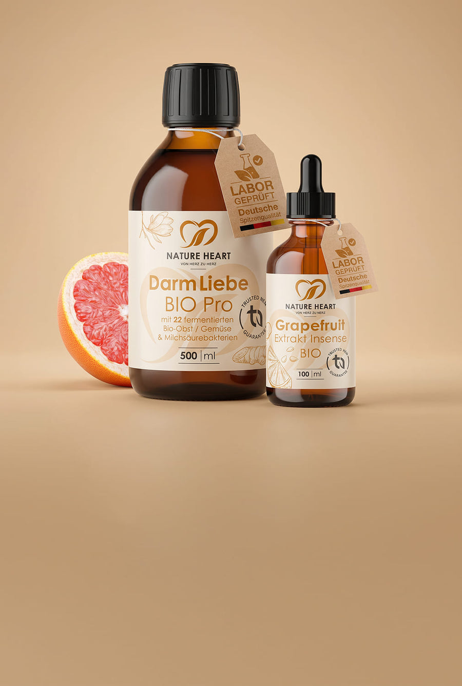 Glasbehälter mit Nature Heart DarmLiebe BIO Pro 500 ml und Nature Heart Grapefruit-Extrakt BIO 100 ml auf beigem Hintergrund mit Grapefruit, beide mit sichtbarem Labor-geprüft-Tag „Deutsche Spitzenqualität“.