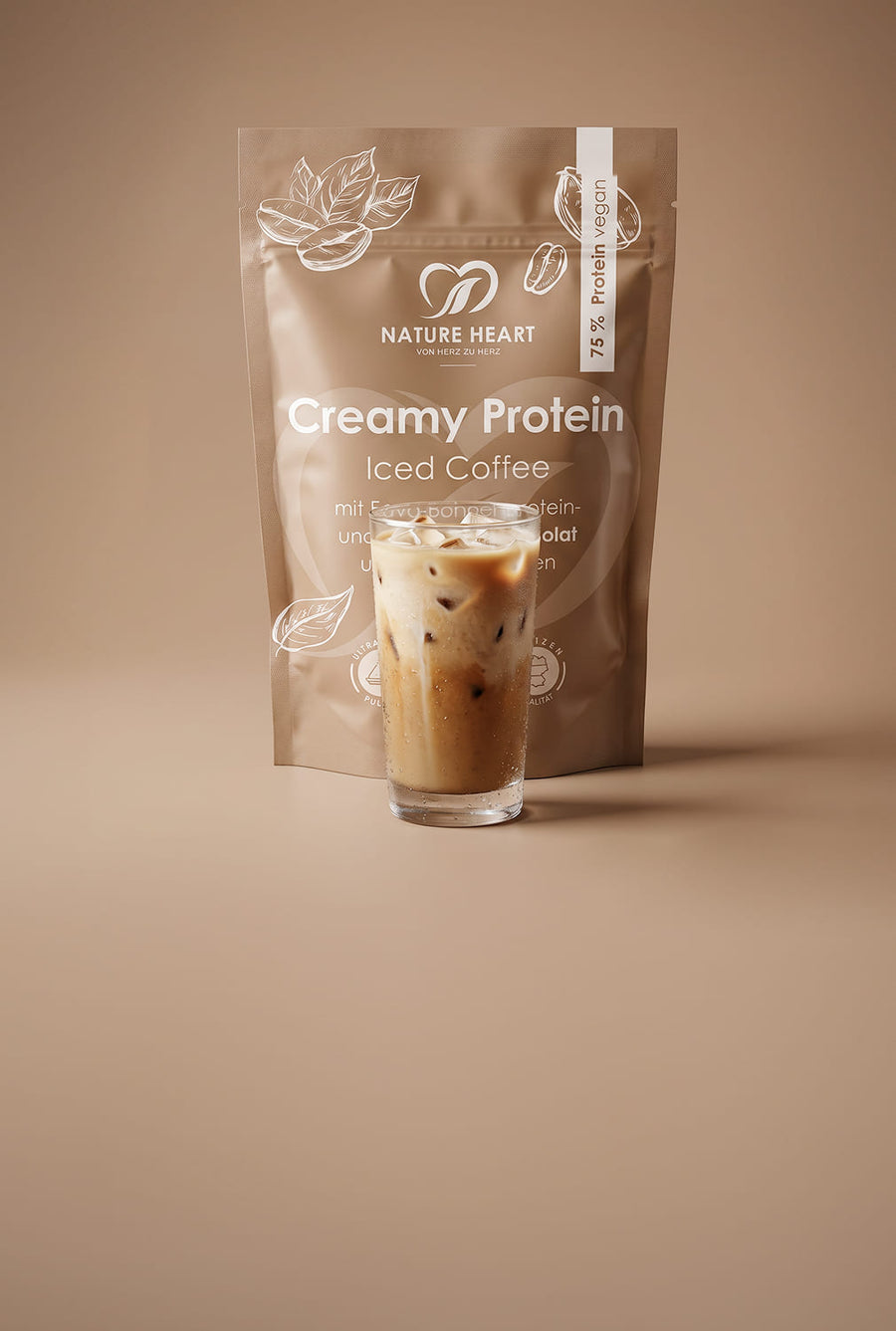 Nature Heart Creamy Protein Iced Coffee in brauner Standverpackung auf beigem Hintergrund, mit sichtbarem Hinweis „75 % Protein vegan“ und einem Glas Iced Coffee davor.