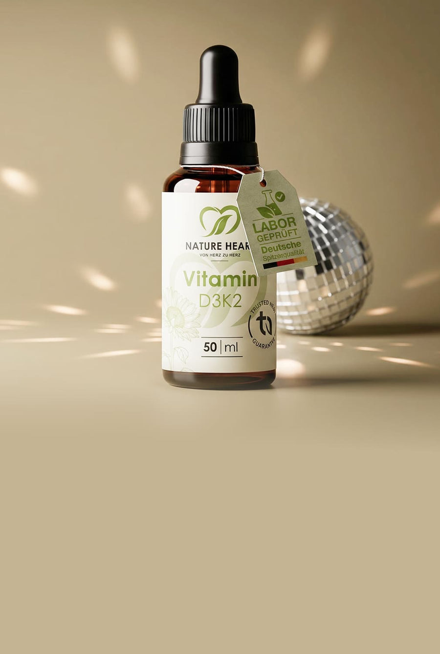 Glasbehälter mit Nature Heart Vitamin D3K2 50 ml auf beigem Hintergrund mit Discokugel-Lichtreflexen, mit sichtbarem Labor-geprüft-Tag „Deutsche Spitzenqualität“.