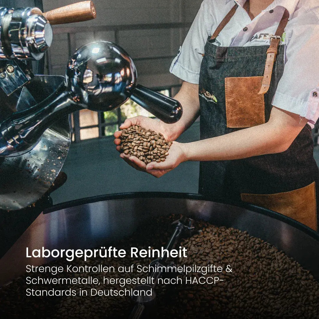 Röster hält frisch geröstete Kaffeebohnen am Trommelröster: laborgeprüft auf Schimmelpilzgifte und Schwermetalle