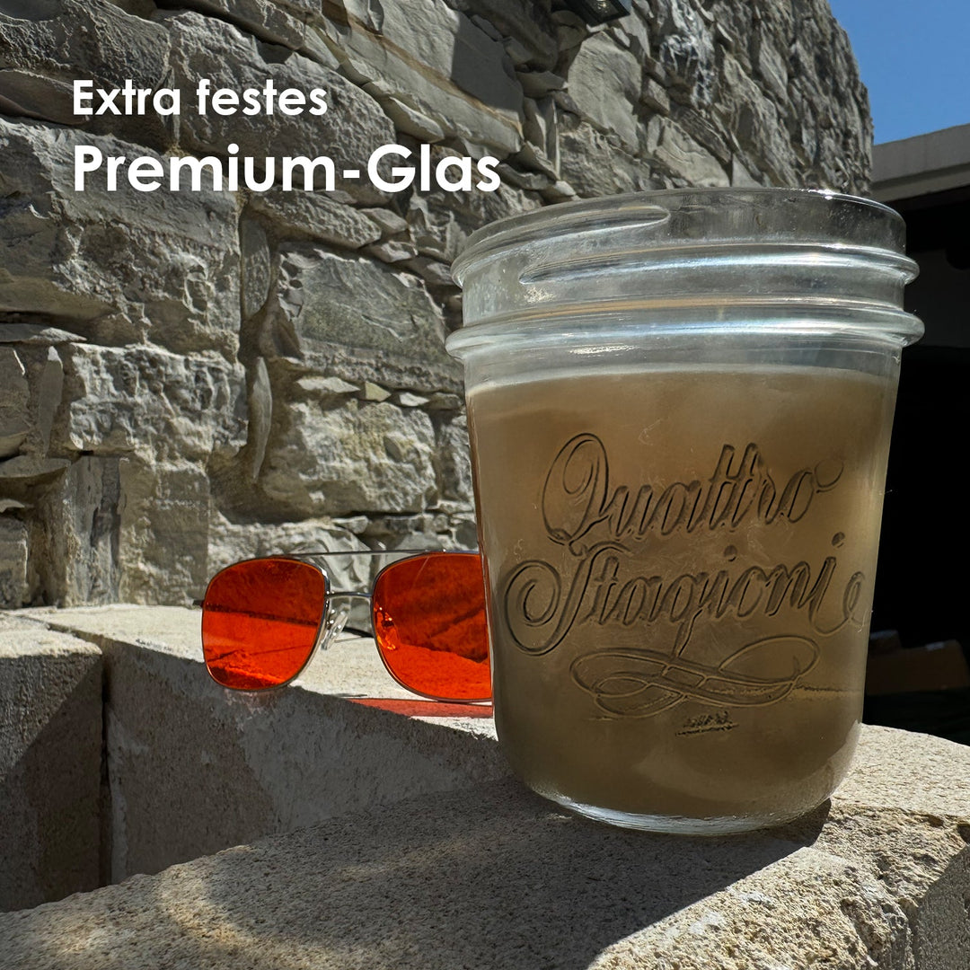 Gefülltes Quattro Stagioni Glas auf einer Steinmauer neben roter Sonnenbrille mit der Headline Extra festes Premium-Glas