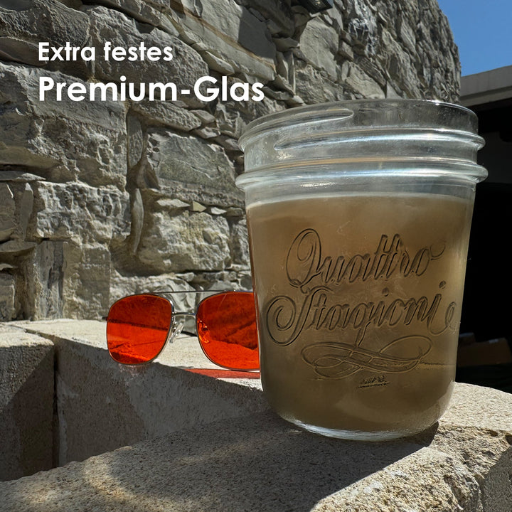 Gefülltes Quattro Stagioni Glas auf einer Steinmauer neben roter Sonnenbrille mit der Headline Extra festes Premium-Glas