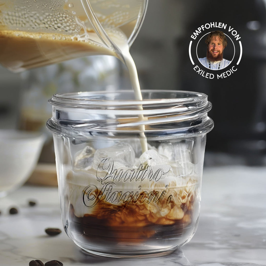 Quattro Stagioni Glas mit Eiswürfeln und Kaffee, in das Milch gegossen wird, mit Badge Empfohlen von Exiled Medic