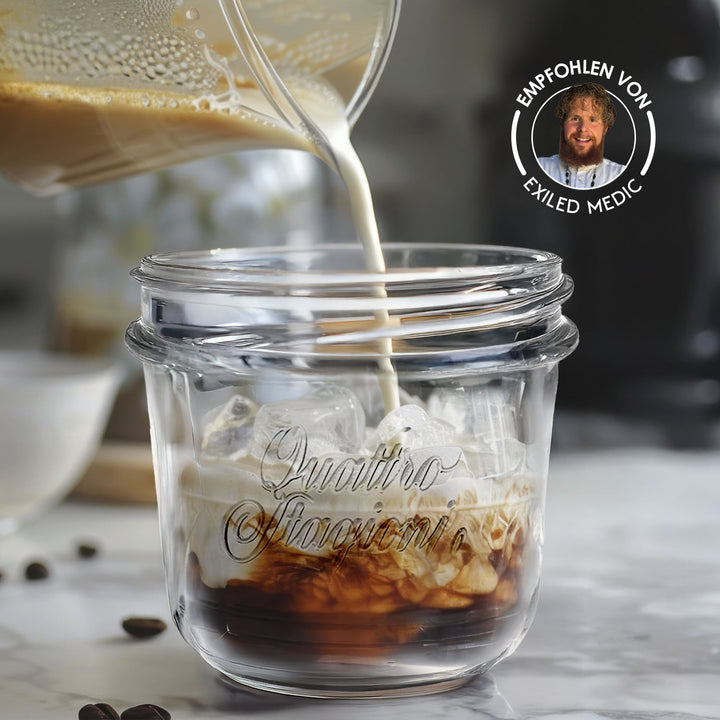 Quattro Stagioni Glas mit Eiswürfeln und Kaffee, in das Milch gegossen wird, mit Badge Empfohlen von Exiled Medic