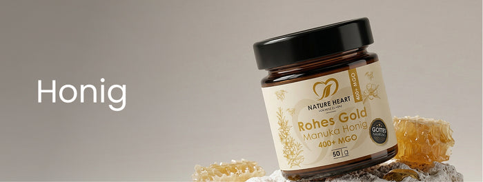 Banner mit der Aufschrift Honig auf hellem Hintergrund, rechts Nature Heart Rohes Gold Manuka Honig 400+ MGO 50 g in einem braunen Glasbehälter mit schwarzem Deckel.