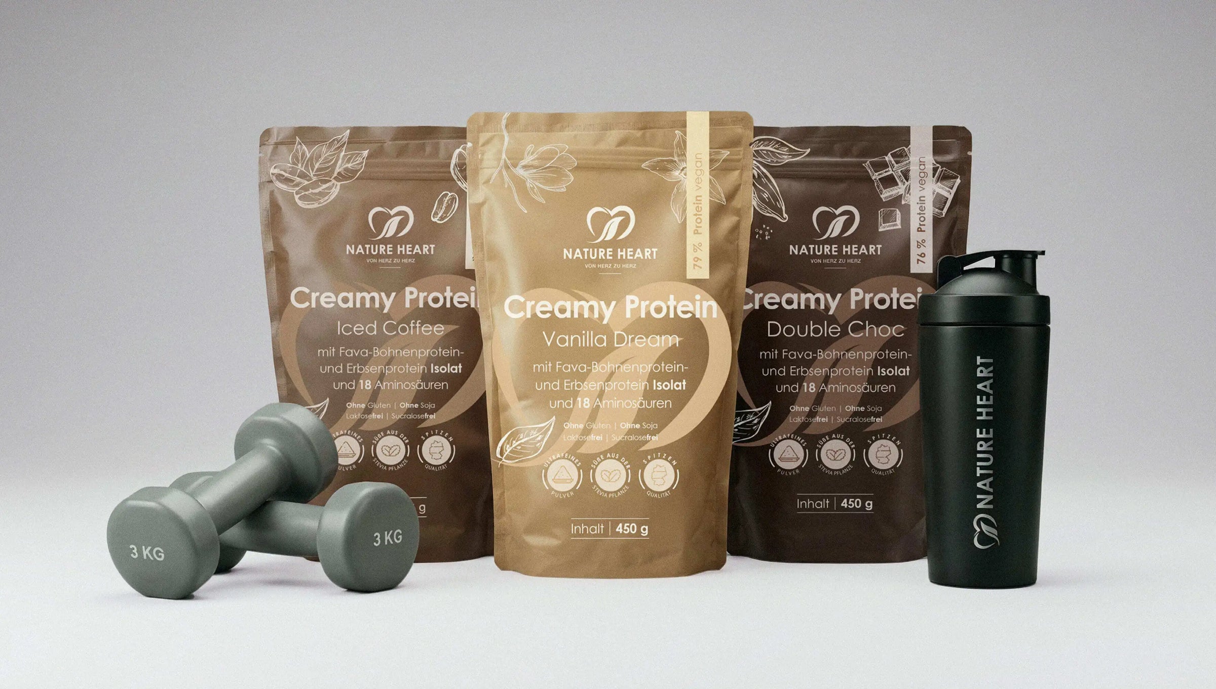 Creamy Protein Iced Coffee, Vanilla Dream und Double Choc 450 g in Standbeuteln mit Hanteln und schwarzem Shaker auf grauem Hintergrund