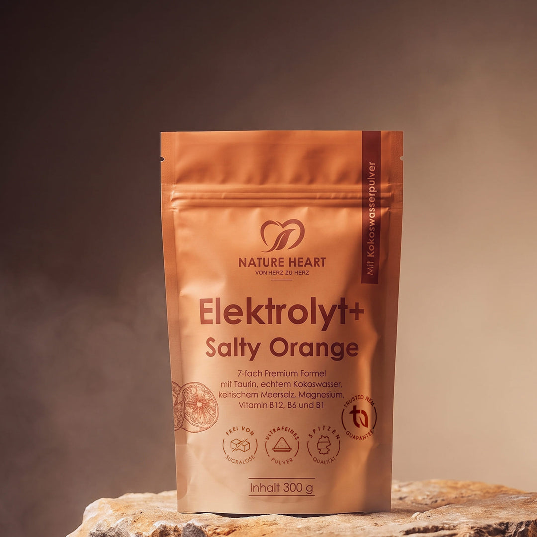Eine orangefarbene Standbodenpackung von Nature Heart mit dem Pulver Elektrolyt+ Salty Orange steht auf einem rustikalen Steinuntergrund vor einem warmen, neutralen Studiohintergrund.