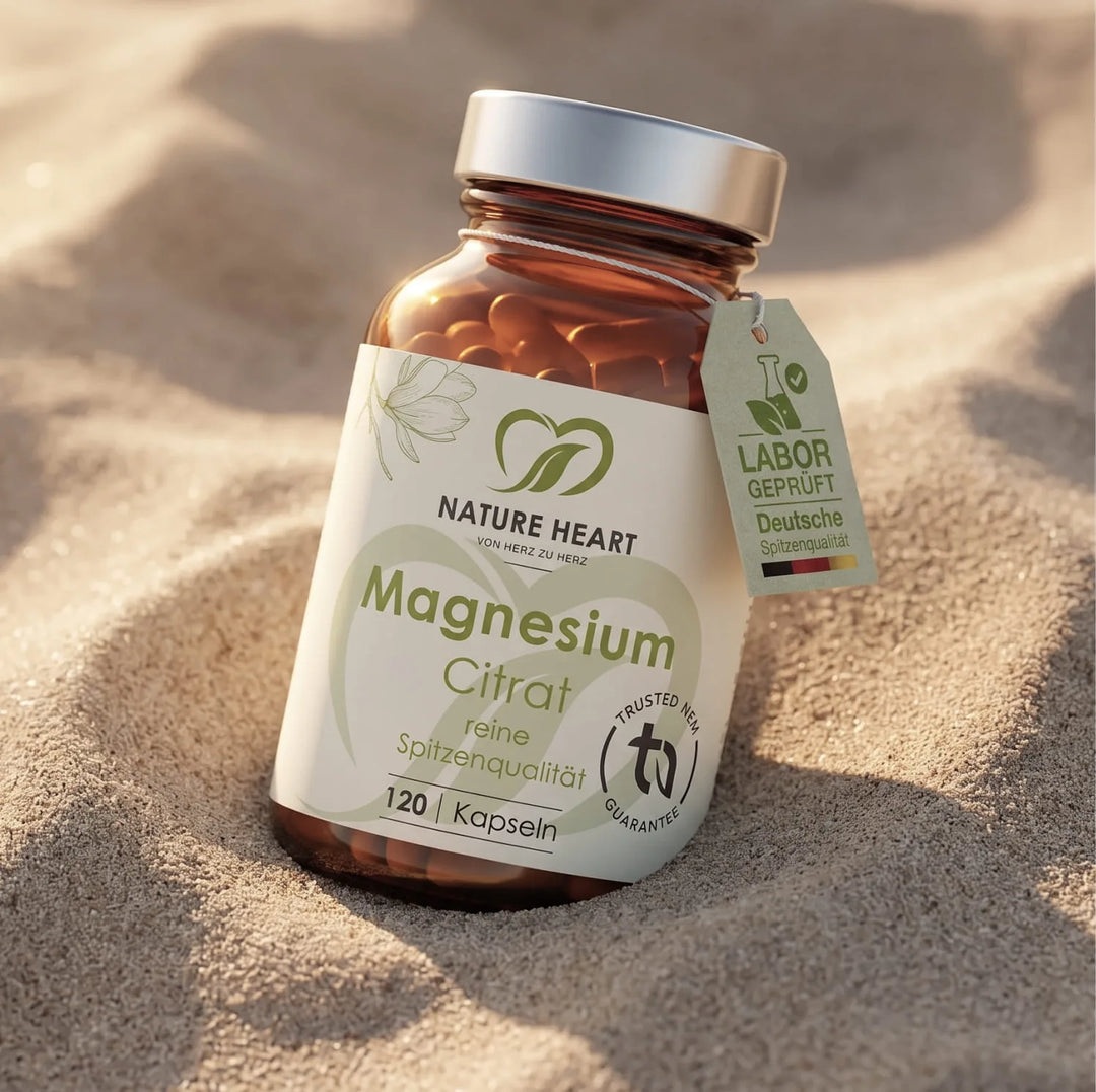 Eine Produktflasche mit Magnesium Citrat Kapseln von Nature Heart, eingebettet in weichem Strandsand. Das Etikett garantiert reine Spitzenqualität für aktive Urlaubstage.