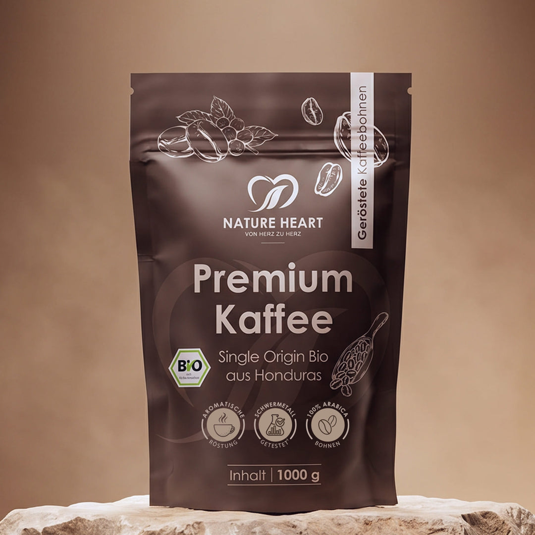 Eine dunkelbraune Kaffeeverpackung von Nature Heart mit gerösteten Premium Kaffeebohnen aus Honduras in Bio-Qualität, platziert auf einem hellen Stein vor beigem Studiohintergrund.