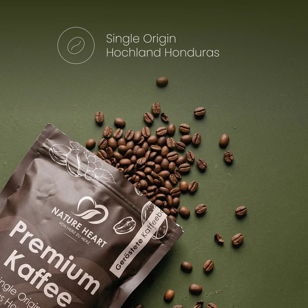 Eine Kaffeeverpackung von Nature Heart Premium Kaffee liegt auf grünem Untergrund neben verstreuten, gerösteten Bohnen unter dem Schriftzug „Single Origin Hochland Honduras“.