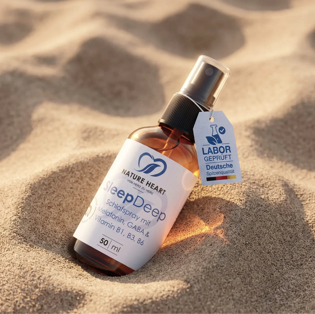 Eine braune Sprühflasche des SleepDeep Schlafsprays von Nature Heart liegt schräg im feinkörnigen Sand. Das Produkt enthält Melatonin sowie GABA und ist ideal für eine erholsame Nacht auf Reisen.