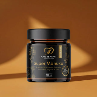 Ein schwarzes 200g-Glas Super Manuka Spezial von Nature Heart mit Schwarzkümmelöl, Curcuma, Ingwer und Zimt vor einem warmen Hintergrund.
