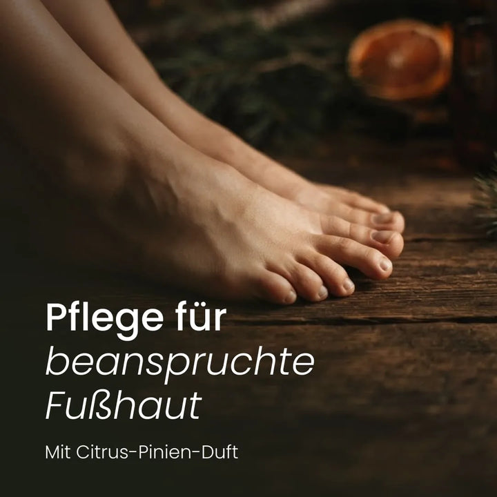 Gepflegte barfüßige Beine auf rustikalem Holzboden mit dem Text „Pflege für beanspruchte Fußhaut – Mit Citrus-Pinien-Duft“.