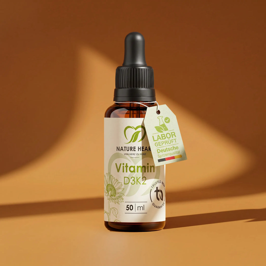 Eine Braunglasflasche mit Pipette der Marke Nature Heart, enthaltend 50 ml Vitamin D3K2 Tropfen vor einem warmen, orangenen Hintergrund.