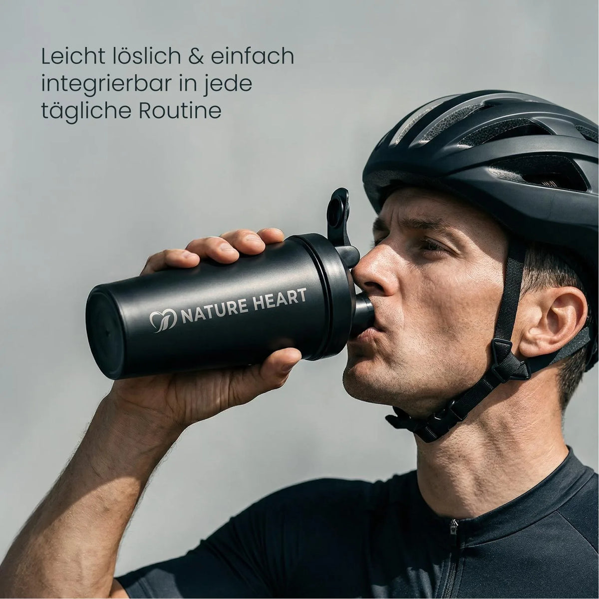 Radfahrer mit Helm trinkt aus einem schwarzen Shaker mit Markenlogo, Hinweis: leicht löslich