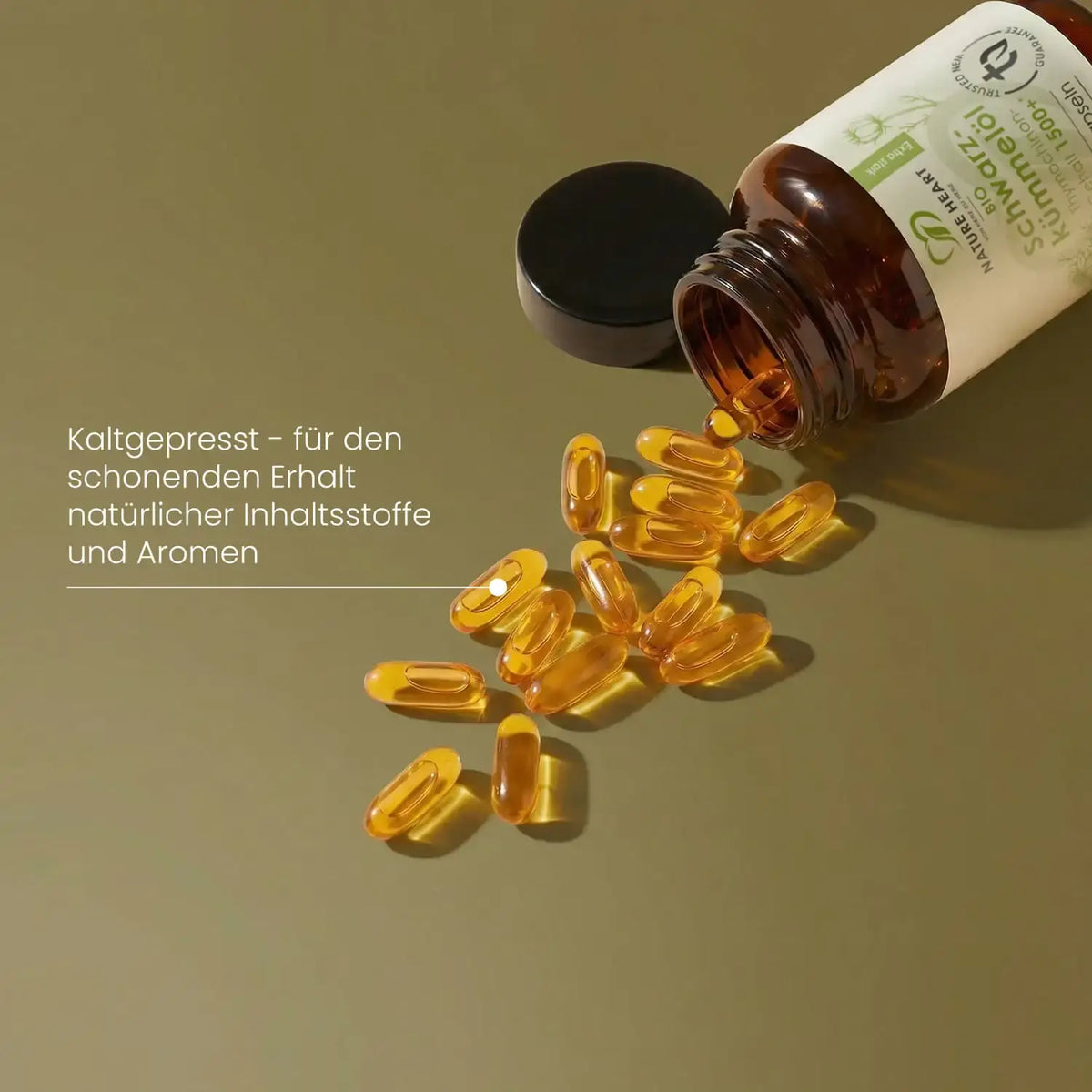 Goldgelbe Weichkapseln fallen aus dem liegenden Braunglas BIO Schwarzkümmelöl 1500+, Öl kaltgepresst hergestellt